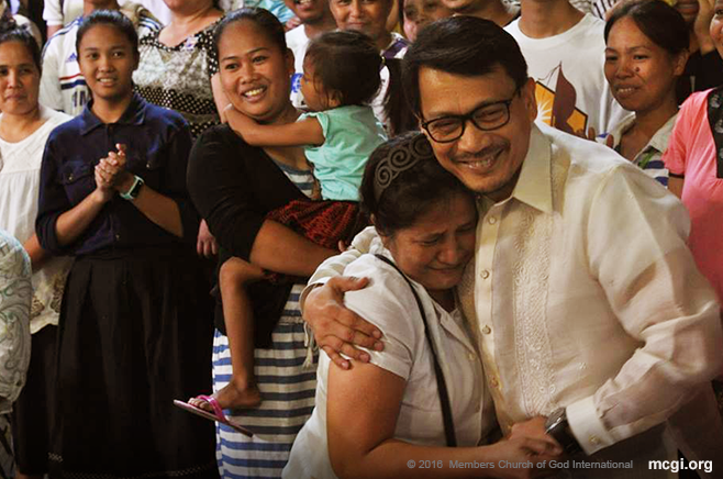 One of the thousand newly-baptized brethren from this year, Sis Amelia Acebuche is overcome with emotion as Bro. Daniel Razon, Assistant Over-all Servant of MCGI, takes a picture with her during her testimony. (Photo courtesy of Photoville International)